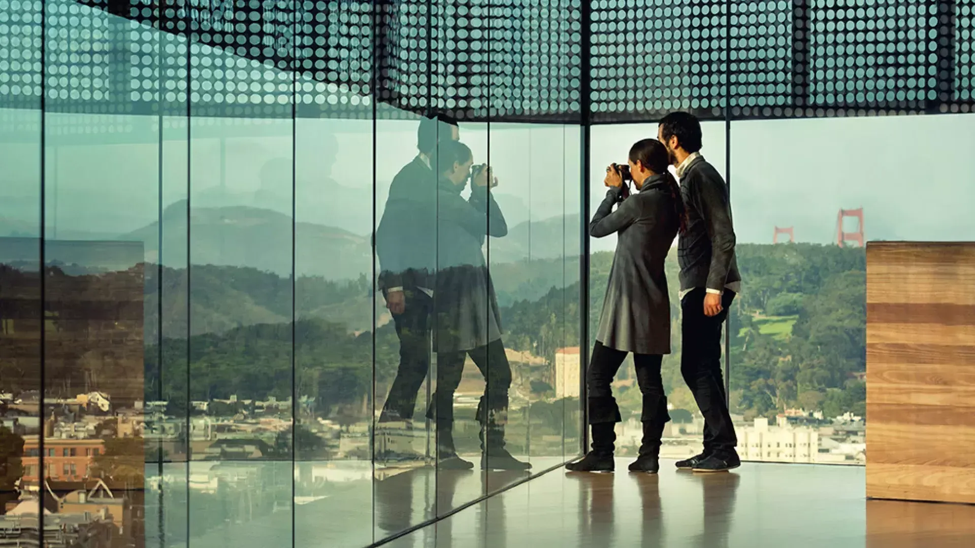 Deux personnes regardent à travers les parois de verre du De Young Museum de San Francisco.