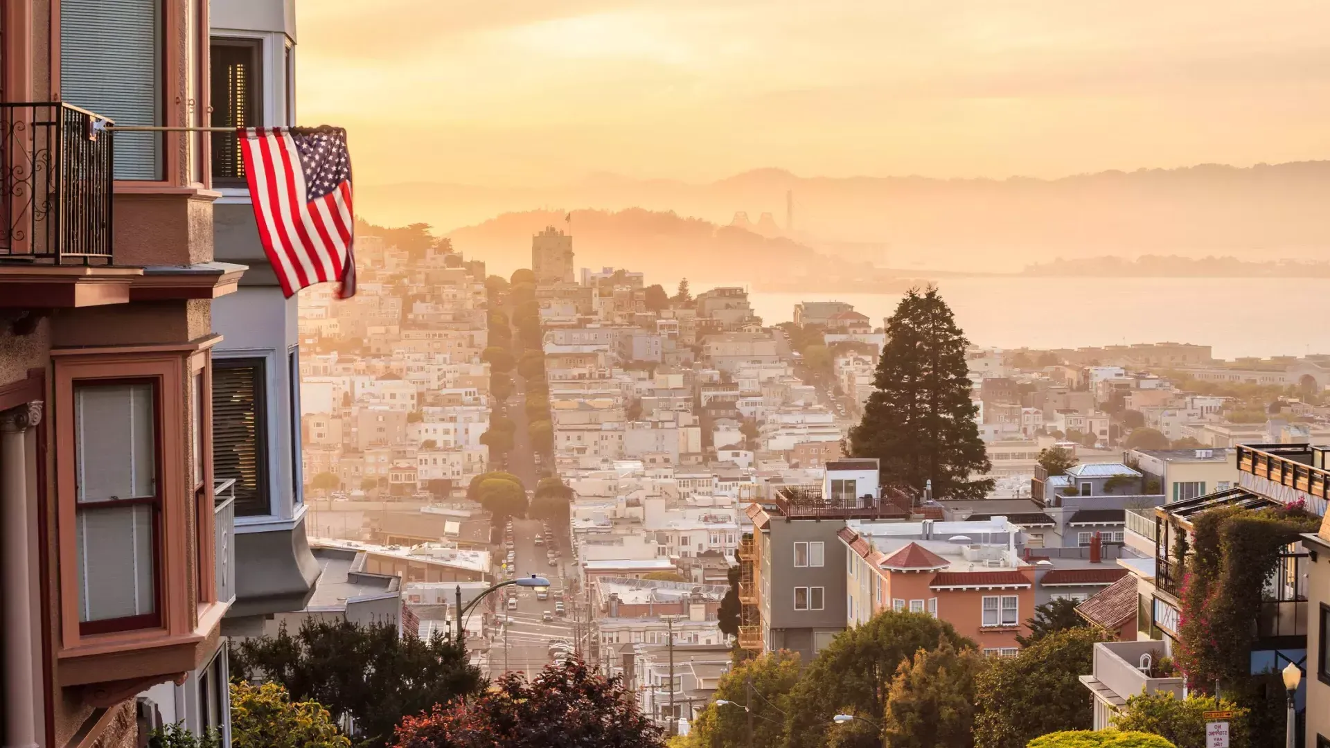 丘の頂上から見たサンフランシスコの眺め。前景にはアメリカ国旗がはためいています。