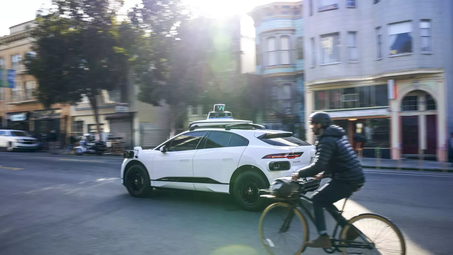 Person riding a bicycle behind a Waymo car