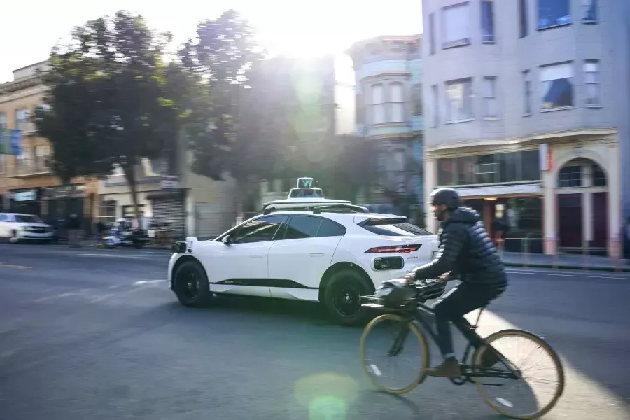 Une personne à vélo derrière une voiture Waymo