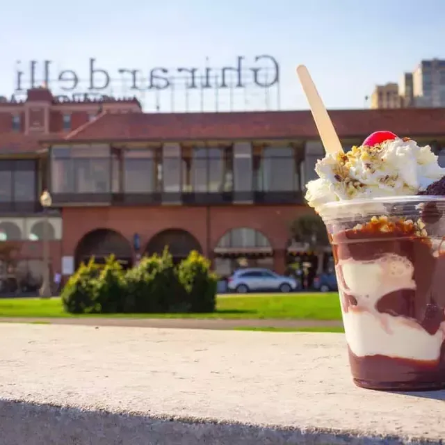 Im Vordergrund steht ein Schokoladenbecher, im Hintergrund der Ghirardelli Square.